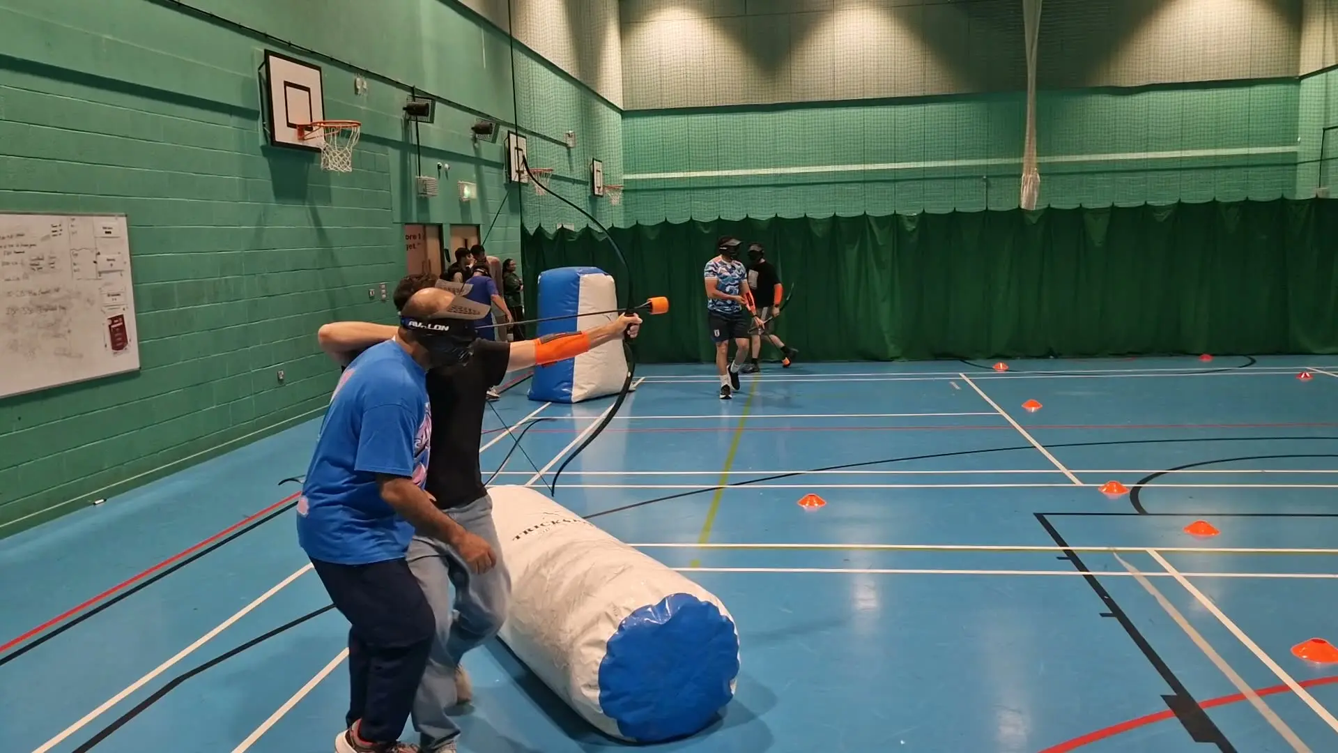 A player takes aim from behind an inflatable bunker in a sports hall